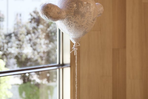 Il guanto con stampa a fumetti raffigurato come un palloncino simboleggia la leggerezza e la libertà che portiamo negli smartphone e in tutto ciò che vi è associato. Il collage su di esso ricorda il linguaggio visivo dei social network e il loro significato inflazionato nella nostra vita quotidiana. Un filo sottile tra necessità e dipendenza. Lo smartphone oscilla incessantemente, come un orologio, senza che ci rendiamo conto del tempo che passa. Lo spettatore può essere incoraggiato da questo "messaggio" a lasciarsi andare e a immergersi in un libro.