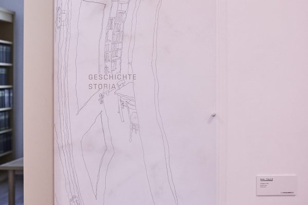 Paul Thuile utilizza le vecchie pareti dell'attuale biblioteca, intrise di storia, come sfondo per i suoi disegni. Vicino allo stipite della porta, posiziona le sue linee inconfondibili come un'anteprima della realtà, uno scorcio dello spazio retrostante. Nella sua ricerca dell'inconsapevole normalità, Paul Thuile esplora attentamente l'ambiente circostante prima di iniziare il lavoro sul posto. I suoi disegni sono la nostra lente d'ingrandimento per vedere i dettagli trascurati e la nostra visione a raggi X per una percezione consapevole dello spazio abitativo.